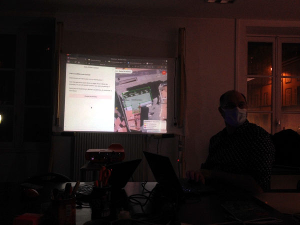 dans la pénombre d'une salle, un écran de vidéoprojecteur présente une interface de saisie d'information géographique.